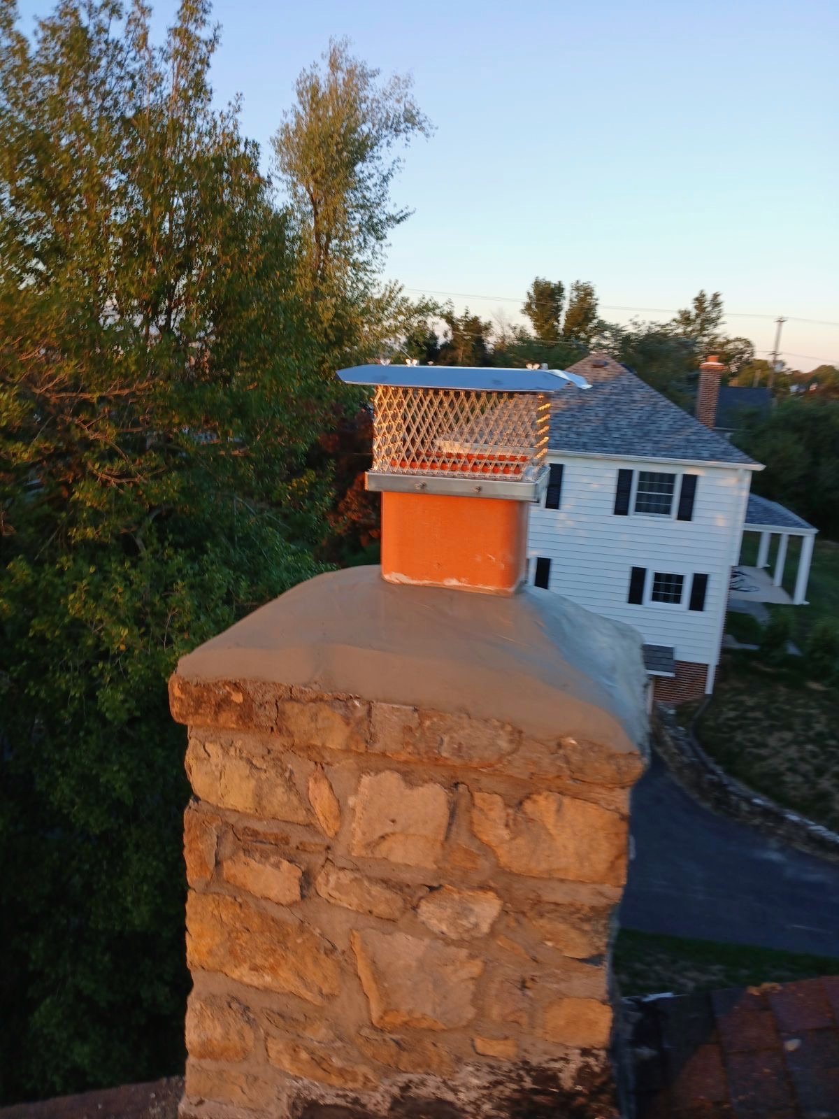 Wire mesh chimney cap installed on a stone chimney